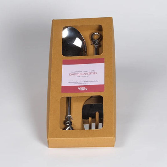 Set of metal salad utensils in a brown box with a white label on a light gray background