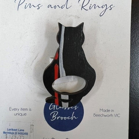 A black cat-shaped scarf pin with a silver and red vertical stripe, mounted on its original white cardboard backing card labeled 'SCARF Pins and Rings'.