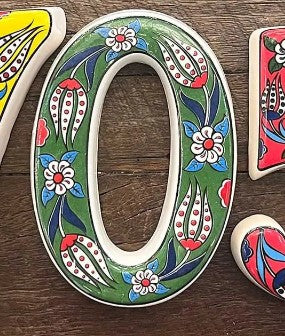 Decorative ceramic number '0' with floral patterns on a wooden surface