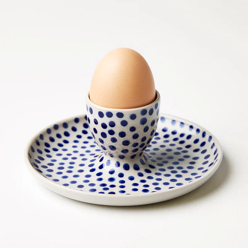 Egg in a polka dot cup on a matching plate with a white background