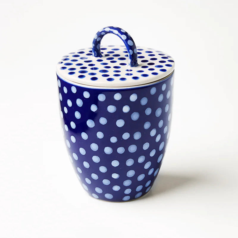 Blue ceramic jar with white polka dots on a white background