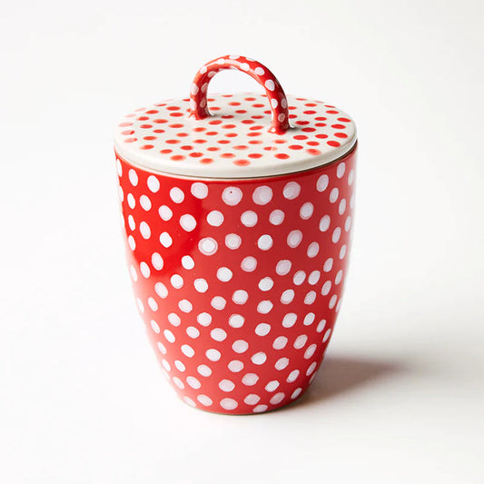 Red ceramic jar with white polka dots and matching lid on a white background