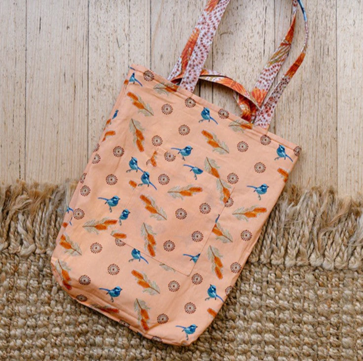 Peach-colored tote bag with bird pattern on a wooden surface