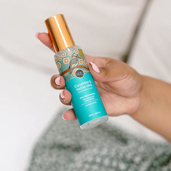 Hand holding a scented body mist bottle.  Cucumber & native minty By Koh Living.