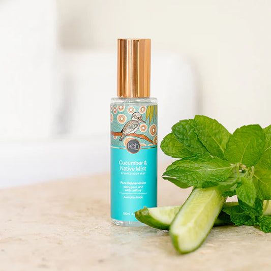 Scented body mist with cucumber and mint leaves on a wooden surface