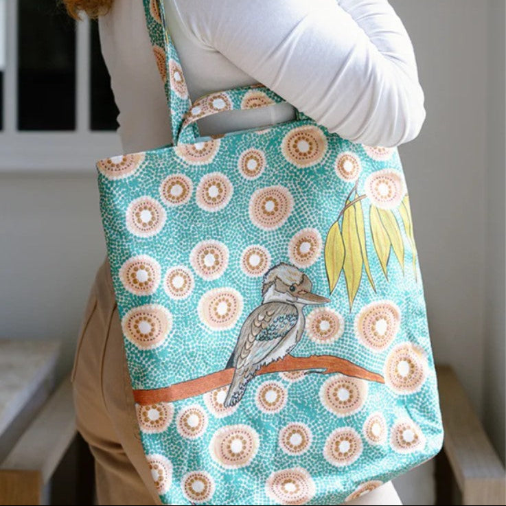 Person holding a tote bag with a bird design and floral pattern.
