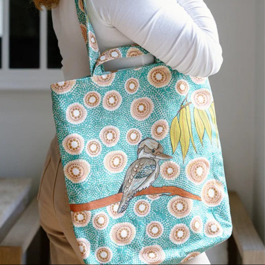 Person holding a tote bag with a bird design and floral pattern.
