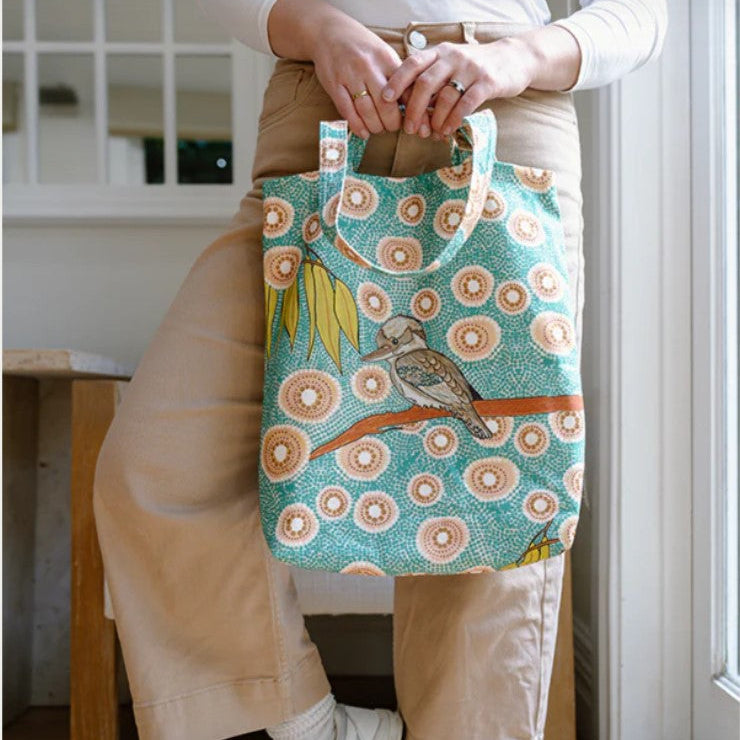 Person holding a patterned tote bag with a bird design in a home setting