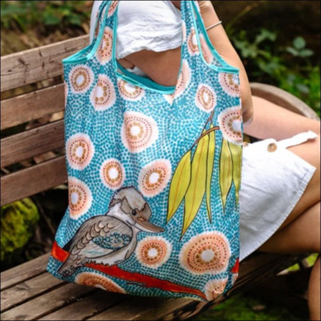 Person holding a colorful tote bag with a duck design outdoors.