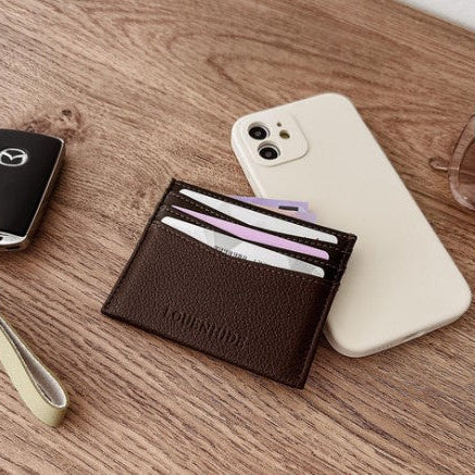 Brown wallet with cards on a wooden surface next to a phone and car key.
