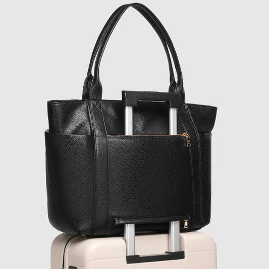 Black bag with a handle on top of a white suitcase against a light gray background