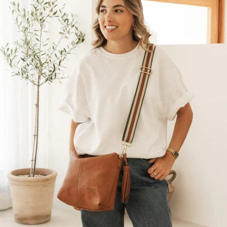 Woman holding a brown bag indoors next to a plant