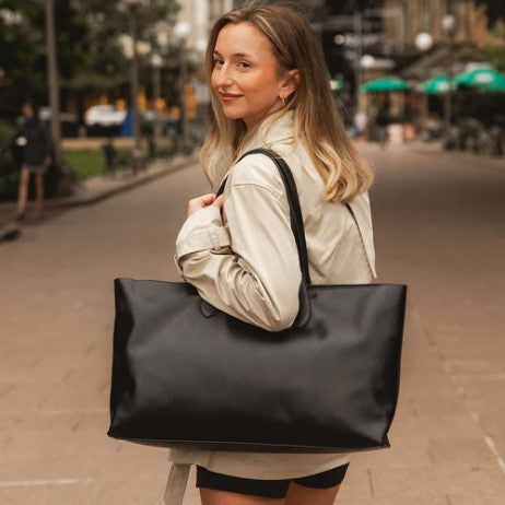 Woman holding a large black tote bag on a city street