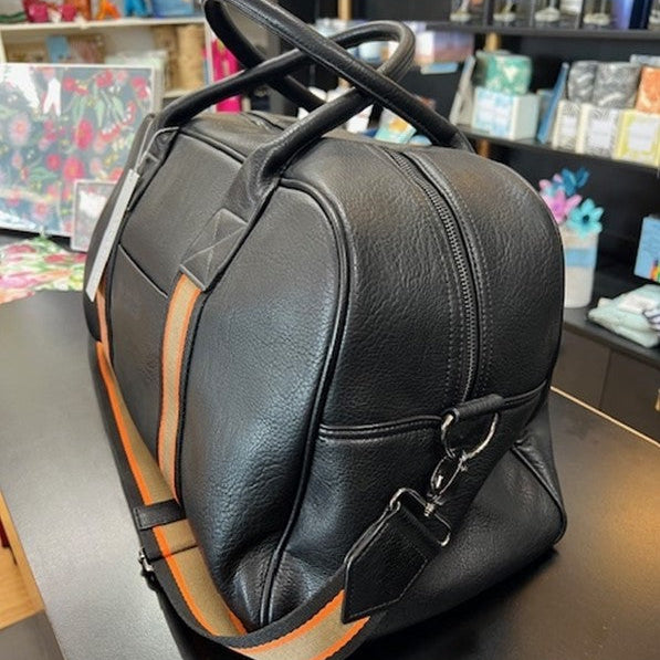 Black leather bag with a strap on a table in a store setting