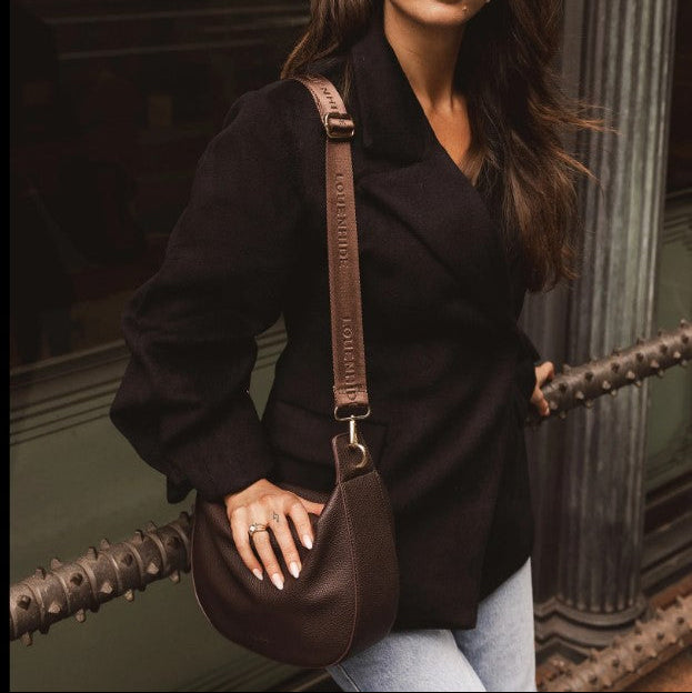 Woman holding a brown bag against a dark background