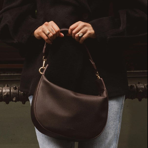 Person holding a brown handbag with a blurred background