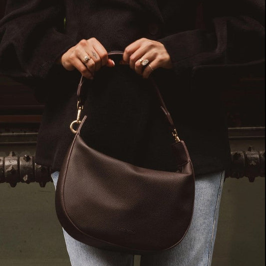 Person holding a brown handbag with a blurred background