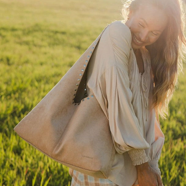 Woman in a beige jacket standing in a field with a warm glow