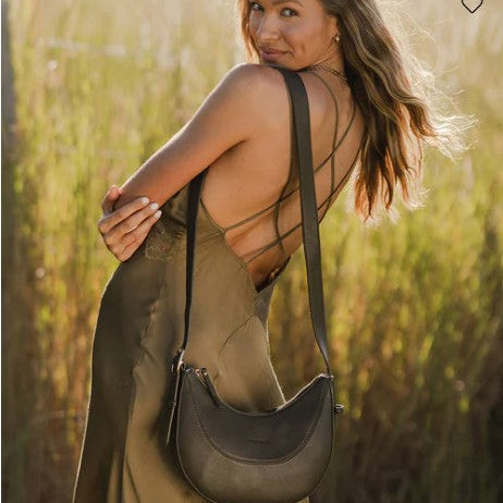 Woman holding a olive handbag in a field