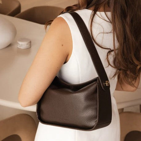 Woman holding a brown handbag in an indoor setting