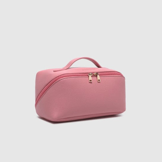 Pink cosmetic bag with gold zippers on a light gray background