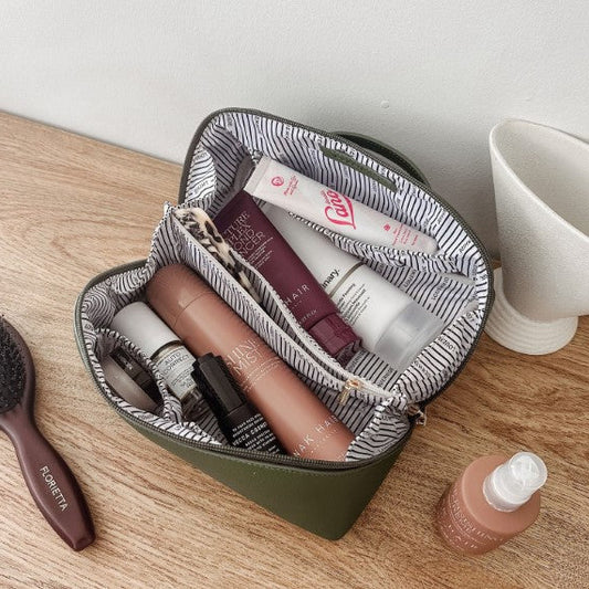Open makeup bag with cosmetic products on a wooden surface