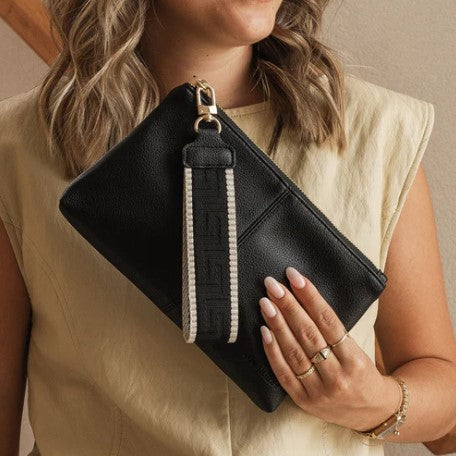 Person holding a black clutch with a visible brand logo.