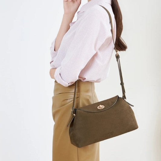 Person wearing a white shirt and brown pants with a brown handbag on a white background
