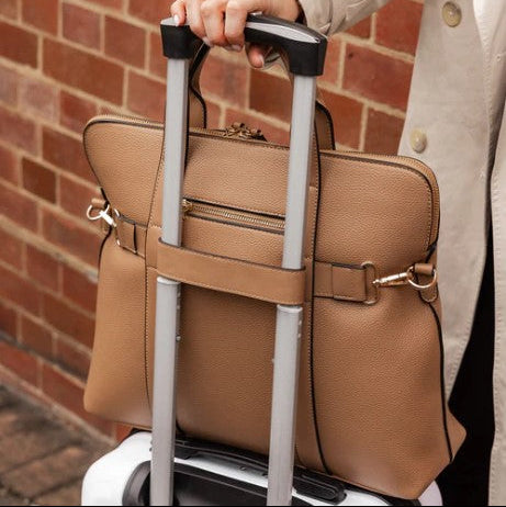 Person carrying a brown laptop bag on a suitcase 