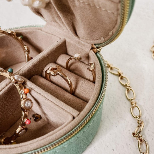 Open jewelry box with gold rings and a chain on a light background