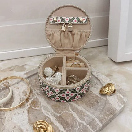 Round jewelry box with floral design on a marble surface