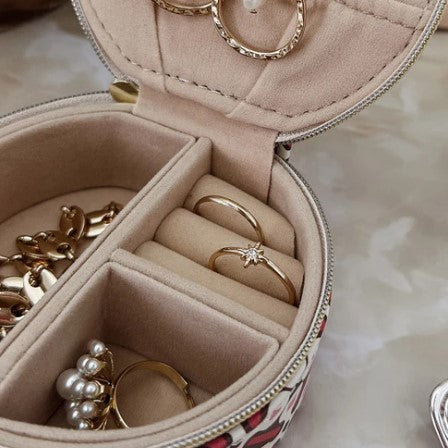 Jewelry set including rings and necklaces in a pink jewelry box on a marble surface.