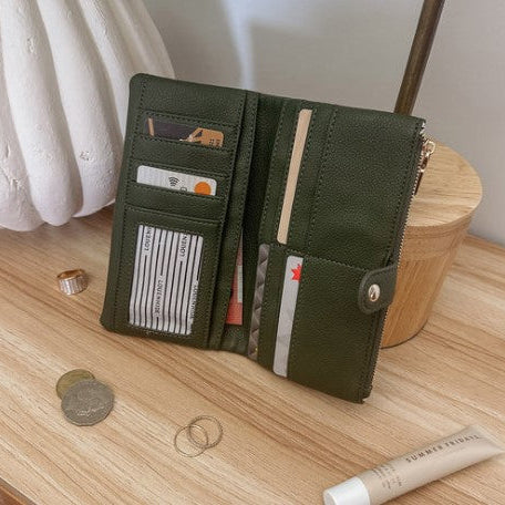 Green wallet with card slots on a wooden surface