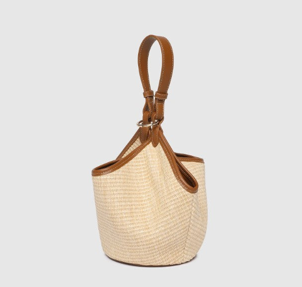 Woven handbag with brown leather accents on a light gray background