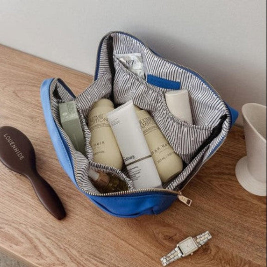 Open toiletry bag with skincare products on a wooden surface