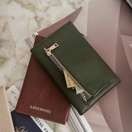 Green wallet with gold zipper on a marble surface