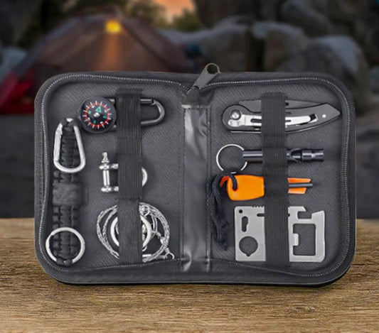Multitool kit with various tools in a black case on a wooden surface with a blurred camping background.