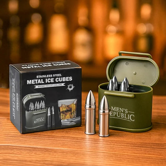 A boxed set of stainless steel bullet-shaped metal ice cubes sits on a wooden table. The black retail box reads 'STAINLESS STEEL METAL ICE CUBES' and shows the Rugged Ridge brand.