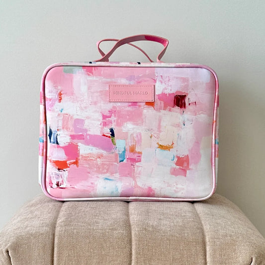 Pink and white abstract patterned suitcase on a beige surface