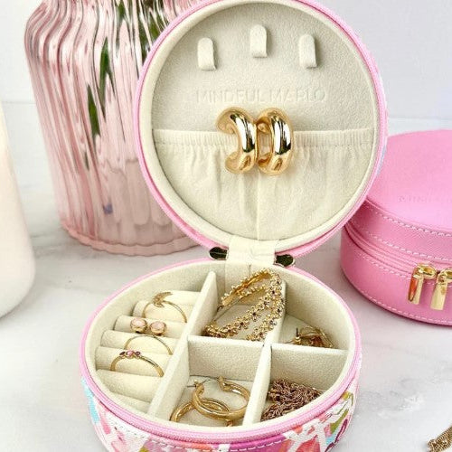 Pink jewelry box with gold jewelry inside on a white surface