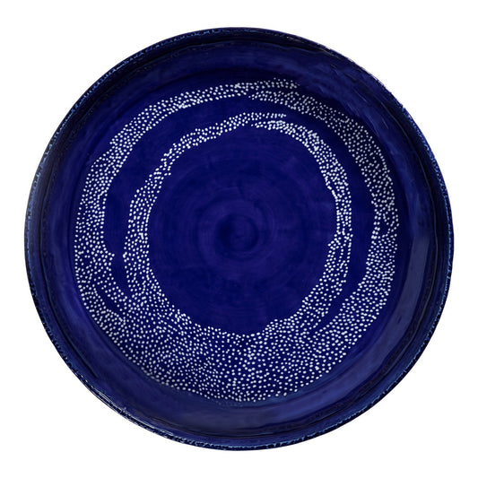 Blue ceramic plate with white dot pattern on a white background
