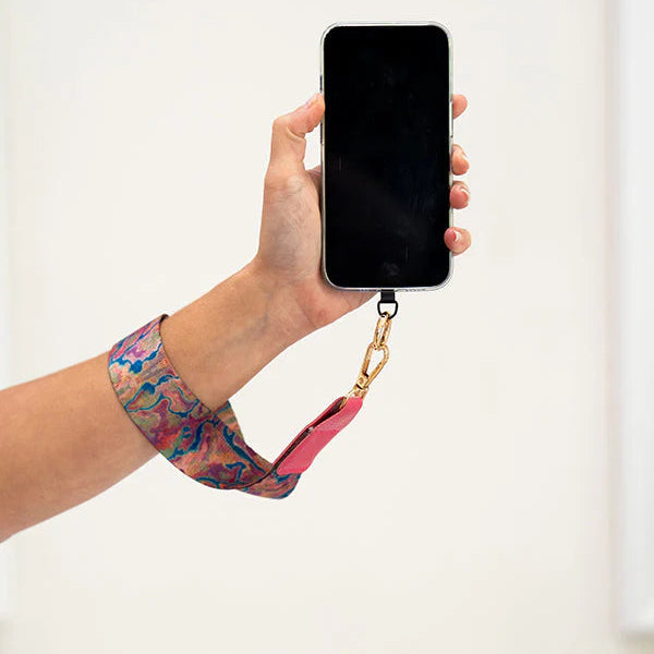 Hand holding a phone with a floral strap against a white background