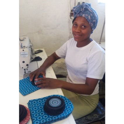 Woman working at a sewing machine with blue fabric and patterns.