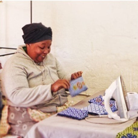 Woman ironing fabric on a bed with an iron box