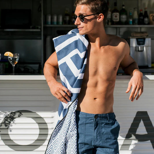 Man holding a blue and white towel with sunglasses.