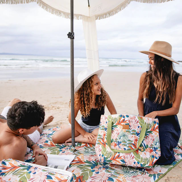 Family on a beach on a floral-patterned picnic rug