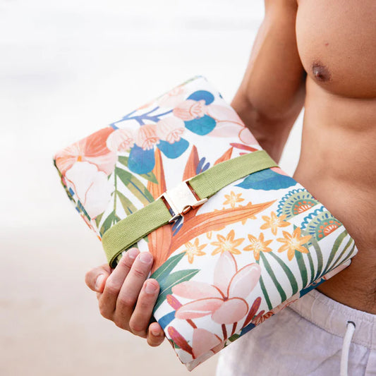 Person holding a floral-patterned picnic mat