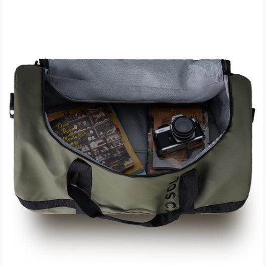 Green duffel bag with camera and books inside on a white background