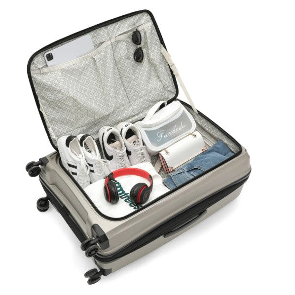 Open suitcase with shoes, a bag, and headphones inside on a white background