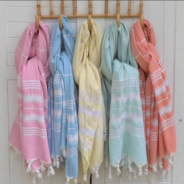 Set of colorful striped towels hanging on a rack against a white wall.